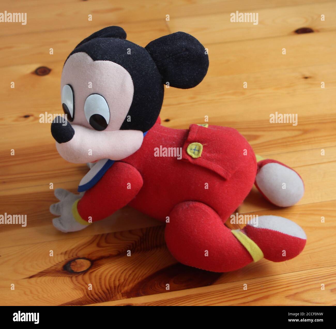 Foto de un oficial de Disney Mickey Mouse crawling bebé alimentado por  batería juguete con un babero y un bebé rojo crecer en un suelo de madera  Fotografía de stock - Alamy