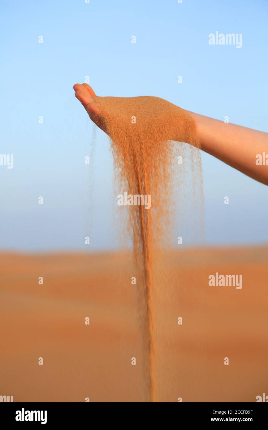 La arena cae de la mano de una mujer Foto de stock