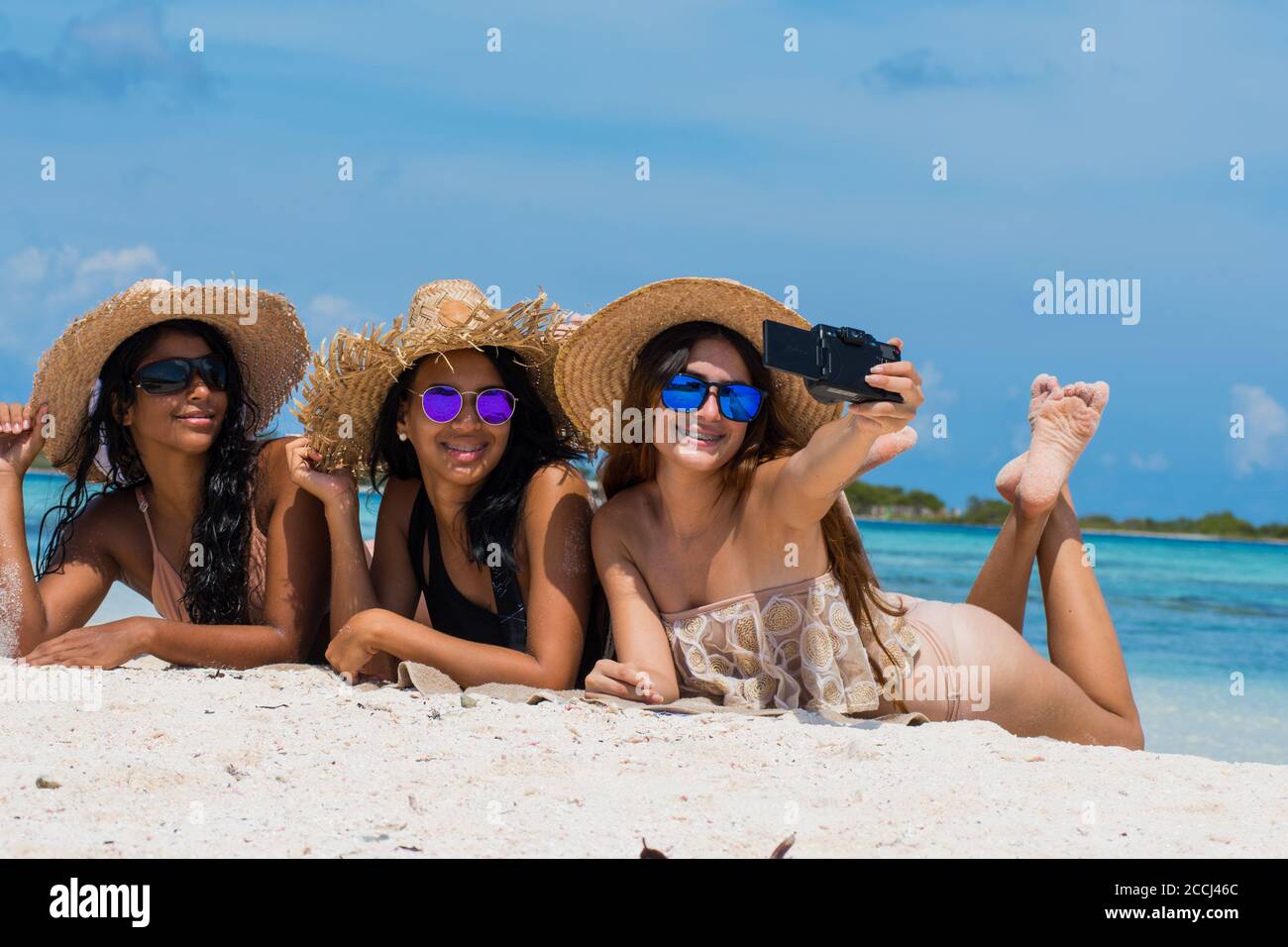 Tres amigas felices en ropa de verano con gafas de sol y. sombrero tomando  un selfie en la playa del caribe Fotografía de stock - Alamy
