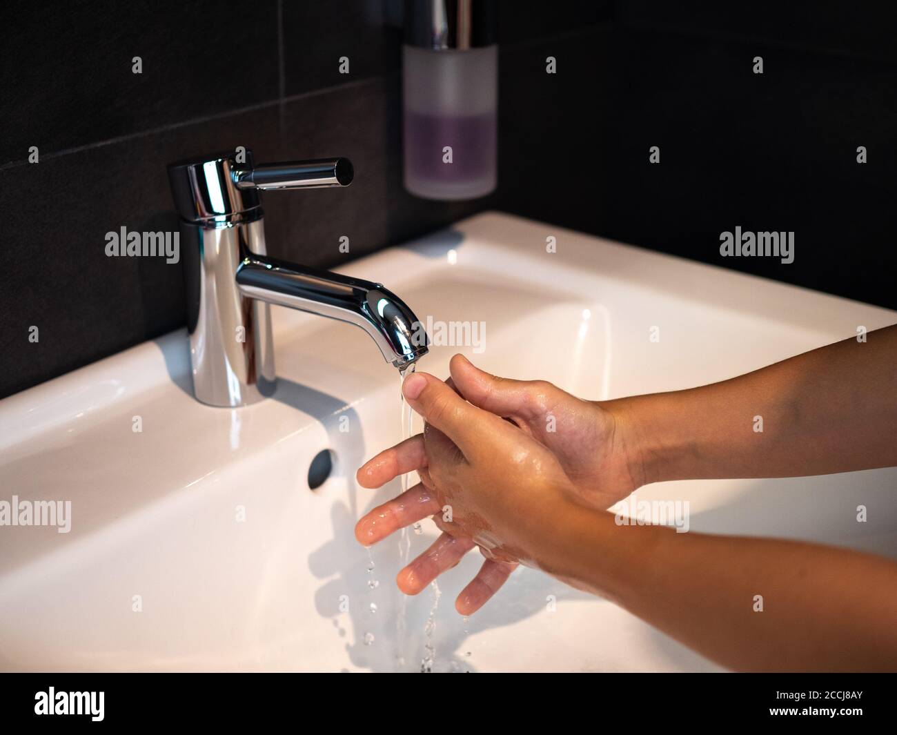 Lavado de manos higiene personal niño lavarse las manos frotar el jabón durante 20 segundos siguiendo los pasos, limpiar las muñecas y enjuagarse bajo el agua en el baño de la casa. Foto de stock