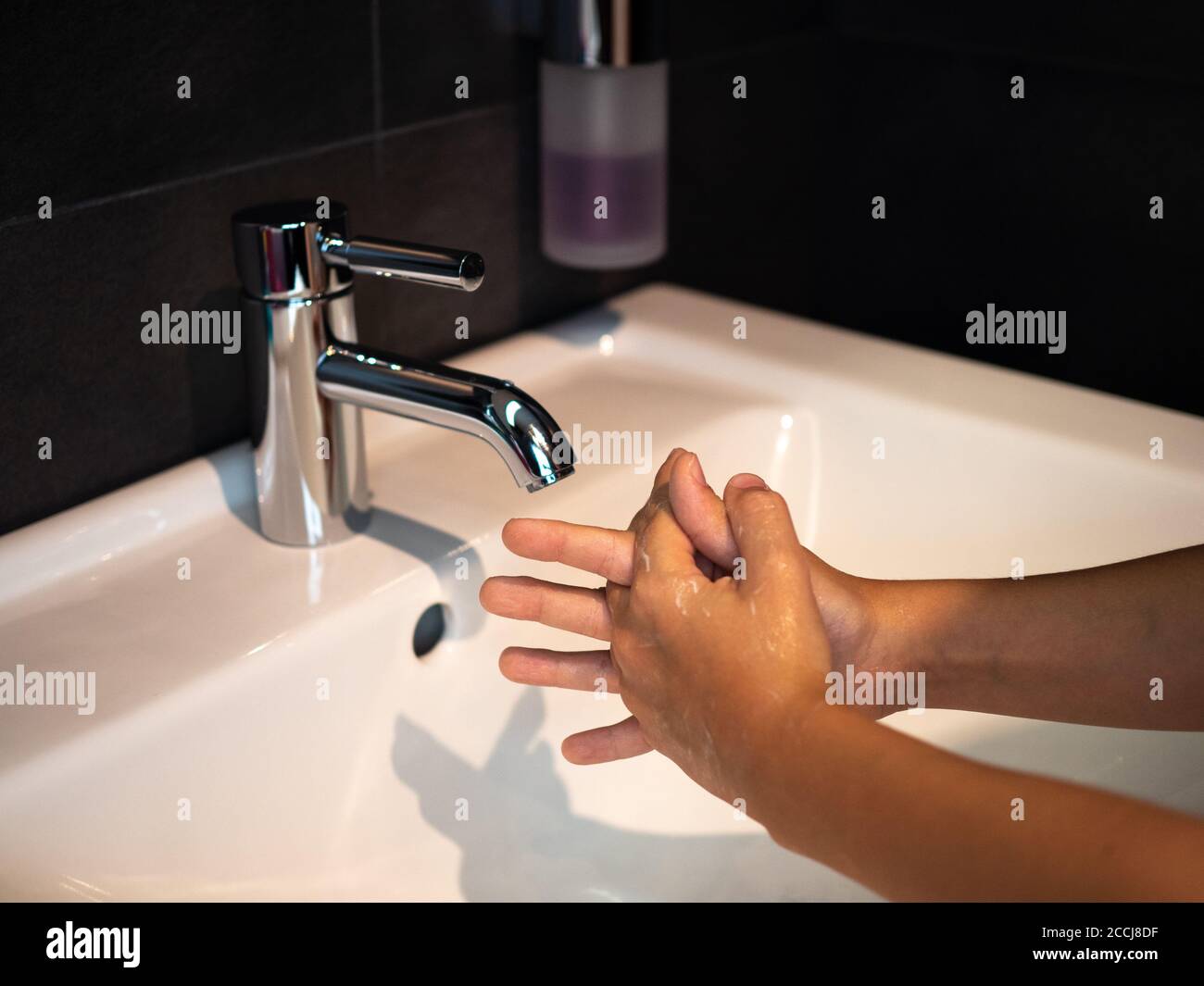 Lavado de manos higiene personal niño lavarse las manos frotar el jabón durante 20 segundos siguiendo los pasos, limpiar las muñecas y enjuagarse bajo el agua en el baño de la casa. Foto de stock