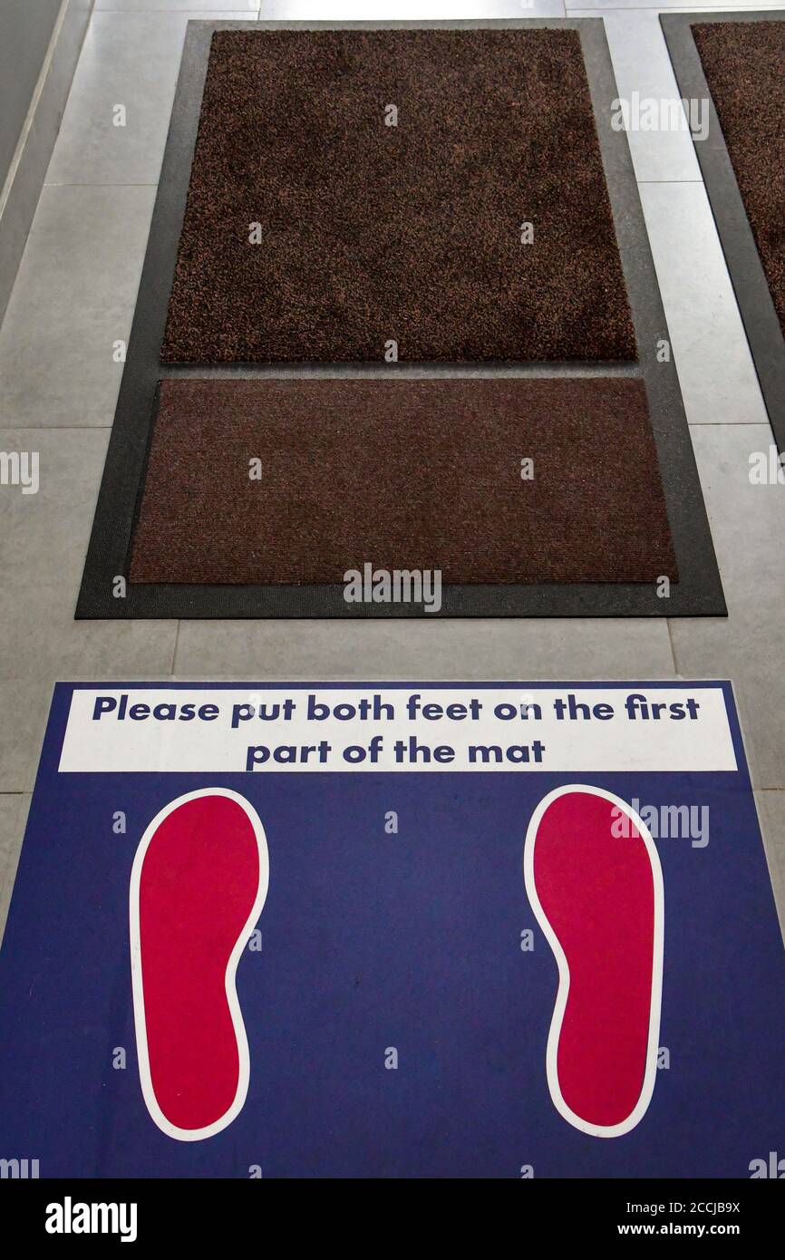 Marcas de suelo e instrucciones para la limpieza de zapatos en un edificio de oficinas durante la pandemia de covid 19. Foto de stock