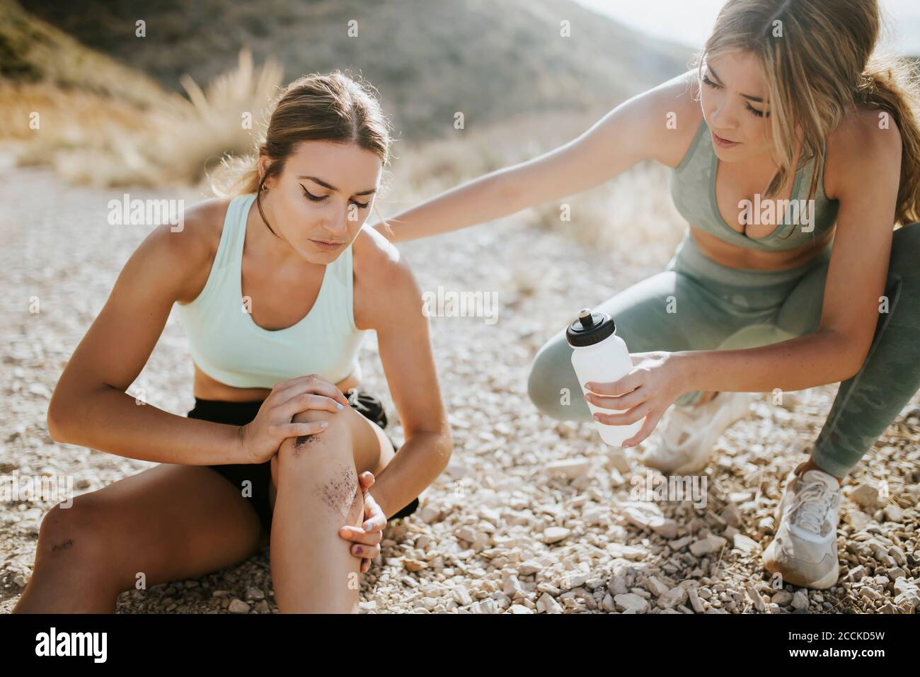 Mujer atleta cuidando a un amigo con una lesión Foto de stock