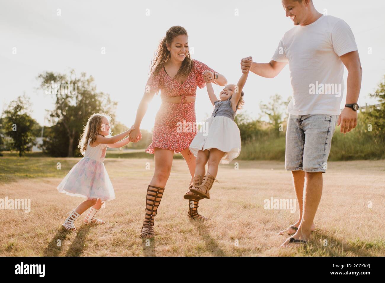 Padres felices jugando con dos hijas en un prado Foto de stock