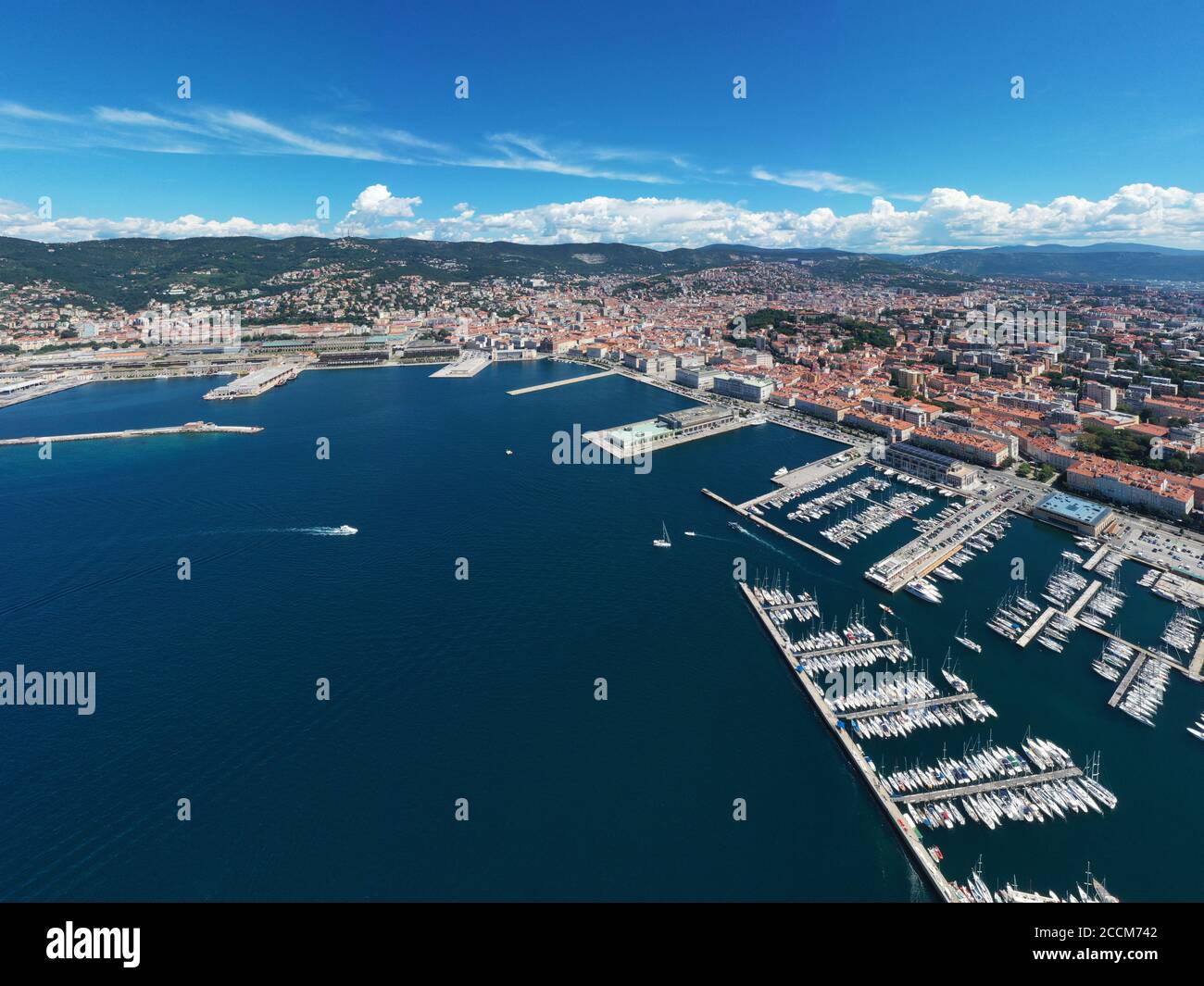 Puerto marítimo de Trieste con numerosos barcos y la ciudad, en una vista panorámica desde arriba durante el día soleado, con el mar azul y el cielo. Foto de stock