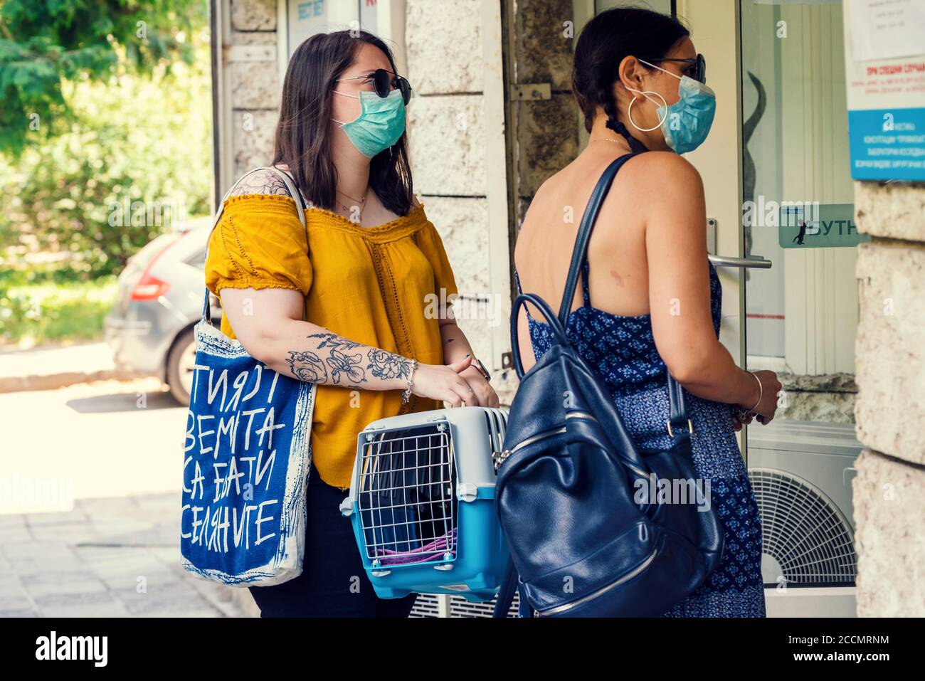 25 de julio de 2020. Sofia,Bulgaria.dos mujeres portando jaula con gato negro esperando delante de la clínica veterinaria para la castración de su mascota.enfoque selectivo Foto de stock