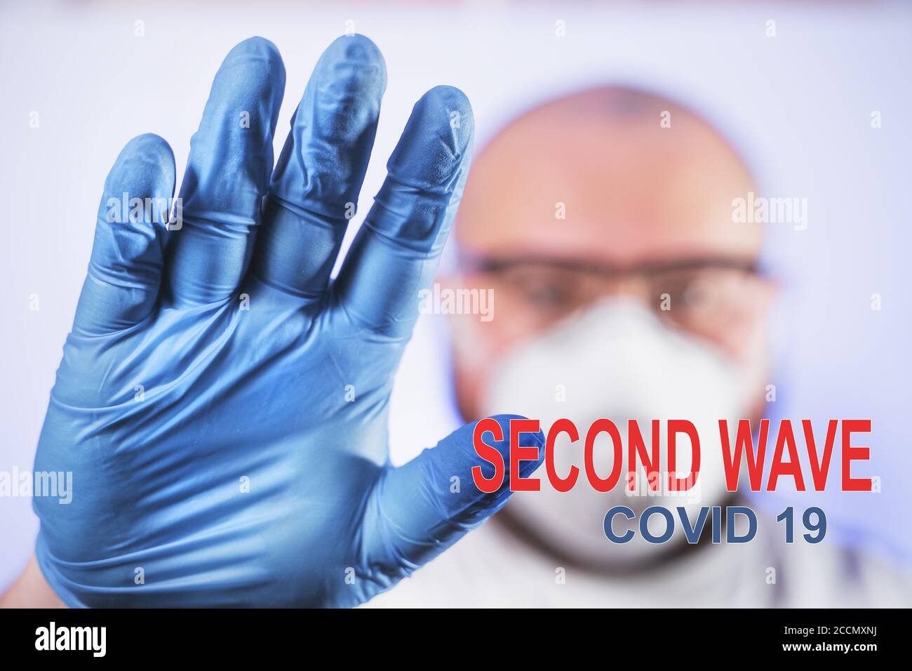 Segunda onda Covid-19 - inscripción en la foto del hombre en máscara y guantes protectores, nueva cuarentena de coronavirus. Foto de stock