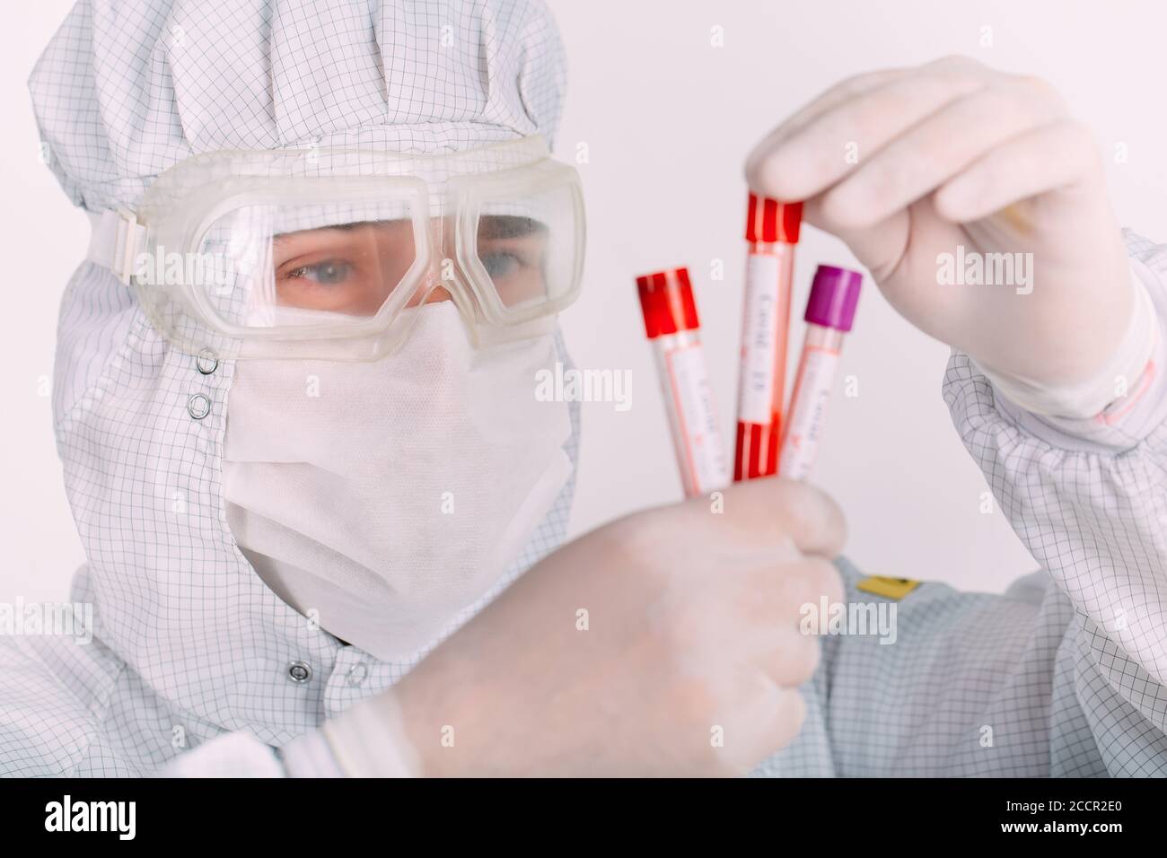doctor hombre en la máscara de la gripe y guantes protectores sosteniendo un tubo de ensayo con una muestra de sangre del coronavirus. Prevenir la gripe Coronavirus. Foto de stock
