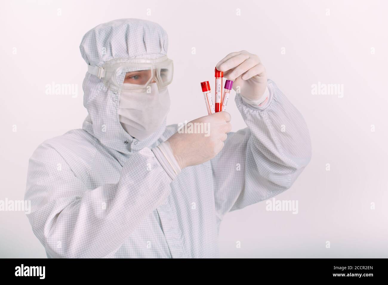 doctor hombre en la máscara de la gripe y guantes protectores sosteniendo un tubo de ensayo con una muestra de sangre del coronavirus. Prevenir la gripe Coronavirus. Foto de stock