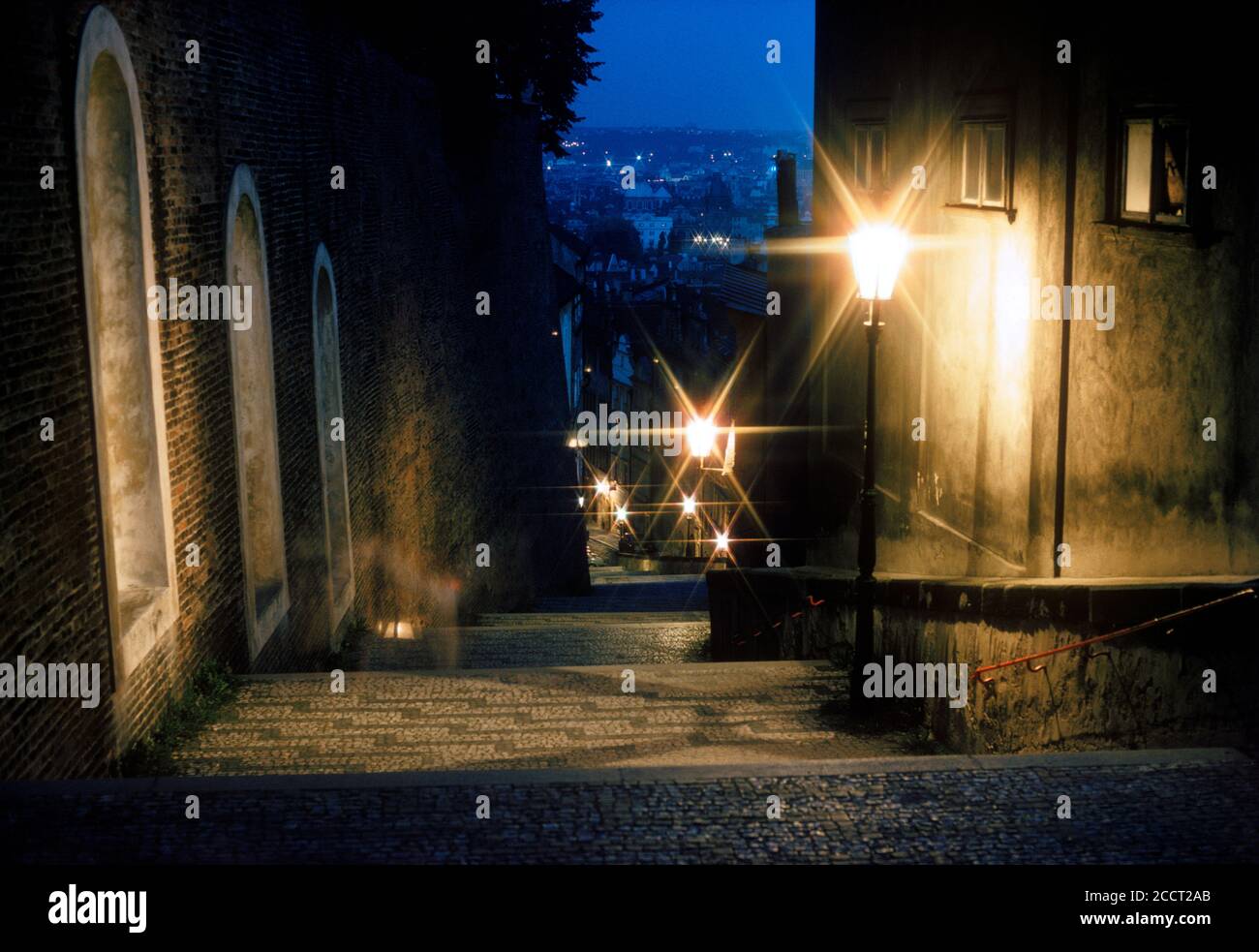 Paso romántico y misterioso de adoquines por la noche en Praga iluminado por la luz Foto de stock