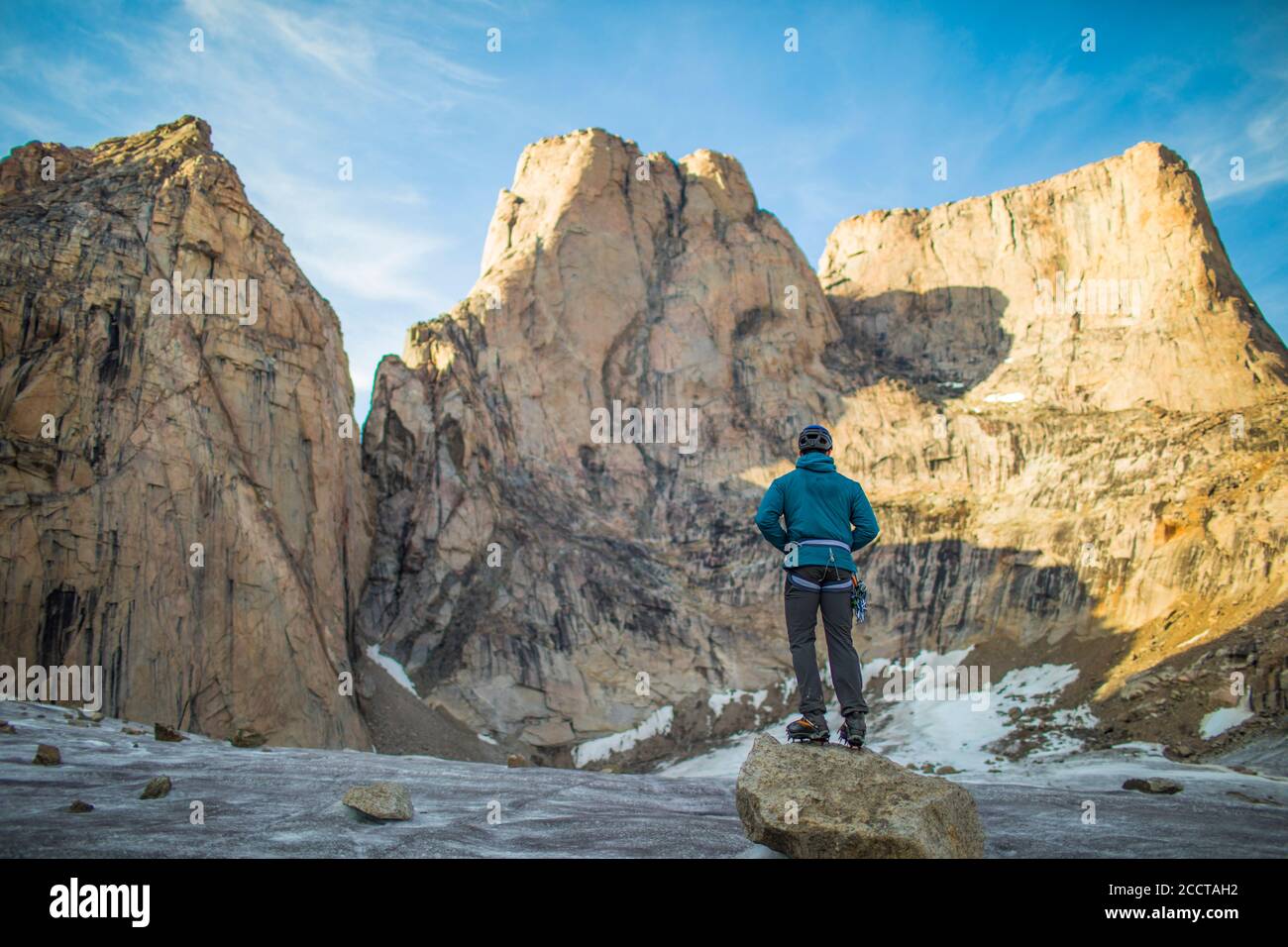 El escalador mira hacia la cima de una montaña antes de escalar. Foto de stock