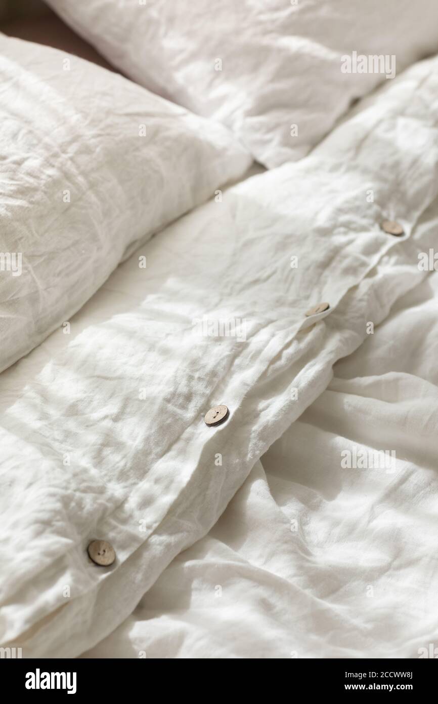 Ropa de cama de lino natural orgánico de moda con botones de madera primer plano. Ropa cama, la mañana, estilo dormitorio y diseño. Fondo textil rugoso con arrugas Fotografía