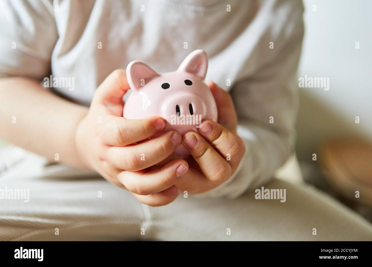 Las manos de los niños tienen el banco de pigmeo rosa como concepto de inversión Foto de stock