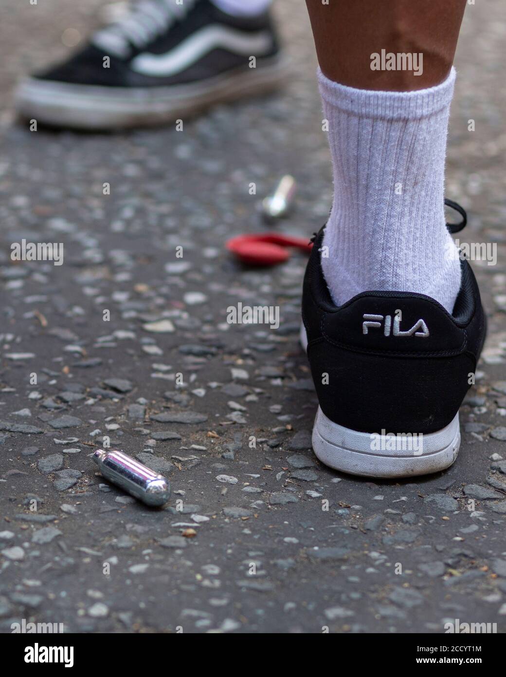 Vista de los pies de un pueblo junto a los botes descartados de óxido nitroso en una carretera durante Notting Hill Carnival, Londres, 2019 Foto de stock