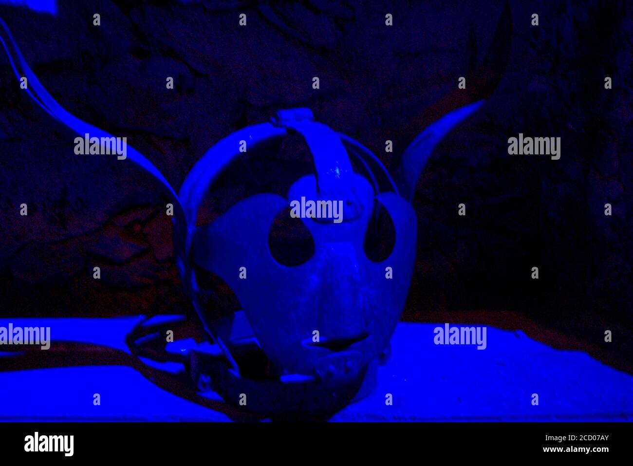 Inusual casco de metal medieval en una iluminación azul espeluznante Foto de stock