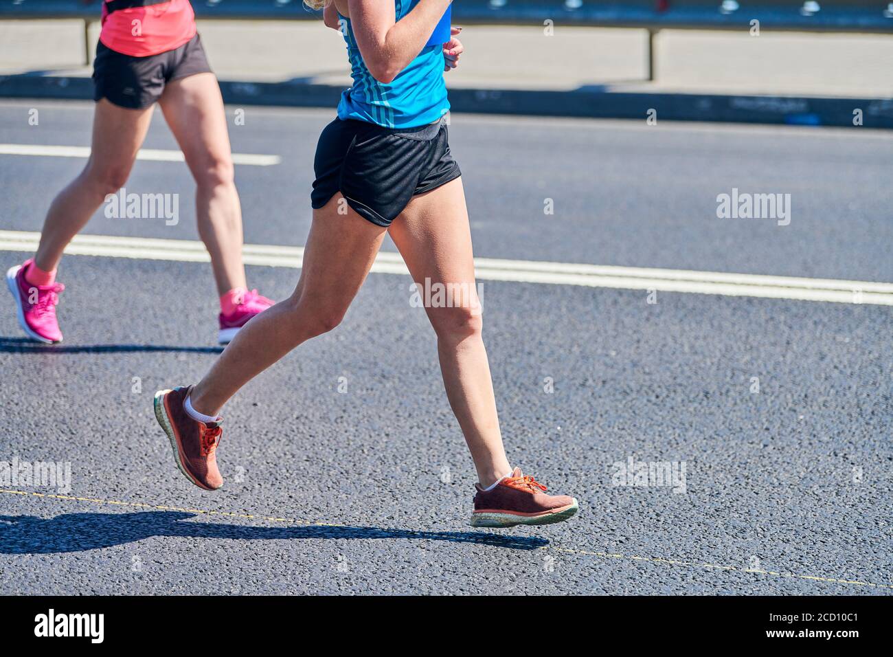 Mujer corriendo. Mujeres deportivas jogging en ropa deportiva en la  carretera de la ciudad. Estilo de vida saludable, afición de fitness.  Carrera de maratón callejera, correr al aire libre Fotografía de stock -