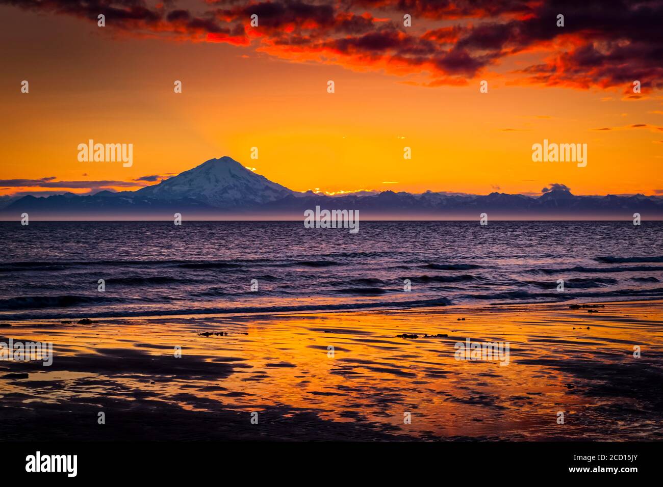 Puesta de sol sobre el Monte Redoubt y la Cordillera Aleutiana, vista a través de Cook Inlet, Península Kenai, centro-sur de Alaska en verano Foto de stock