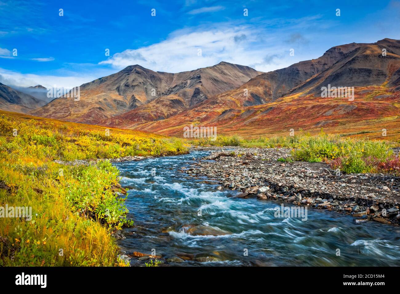 Kuyuktuvuk Creek y montañas Brooks en colores de otoño bajo el cielo azul. Gates of the Arctic National Park and Preserve, Arctic Alaska en otoño Foto de stock