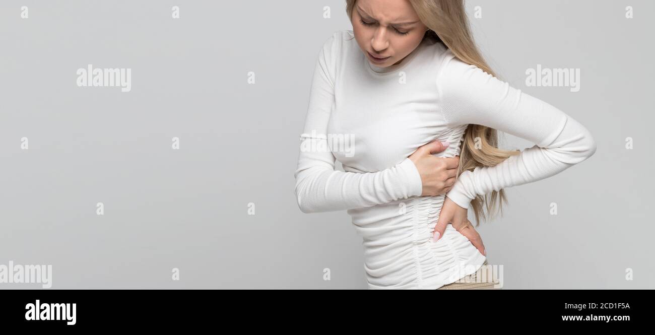 Joven mujer caucásica linda con dolor, dolor muscular o nervioso crónico en la espalda después de trabajar. Enfermedades de la columna vertebral, escoliosis, osteoporosis Foto de stock