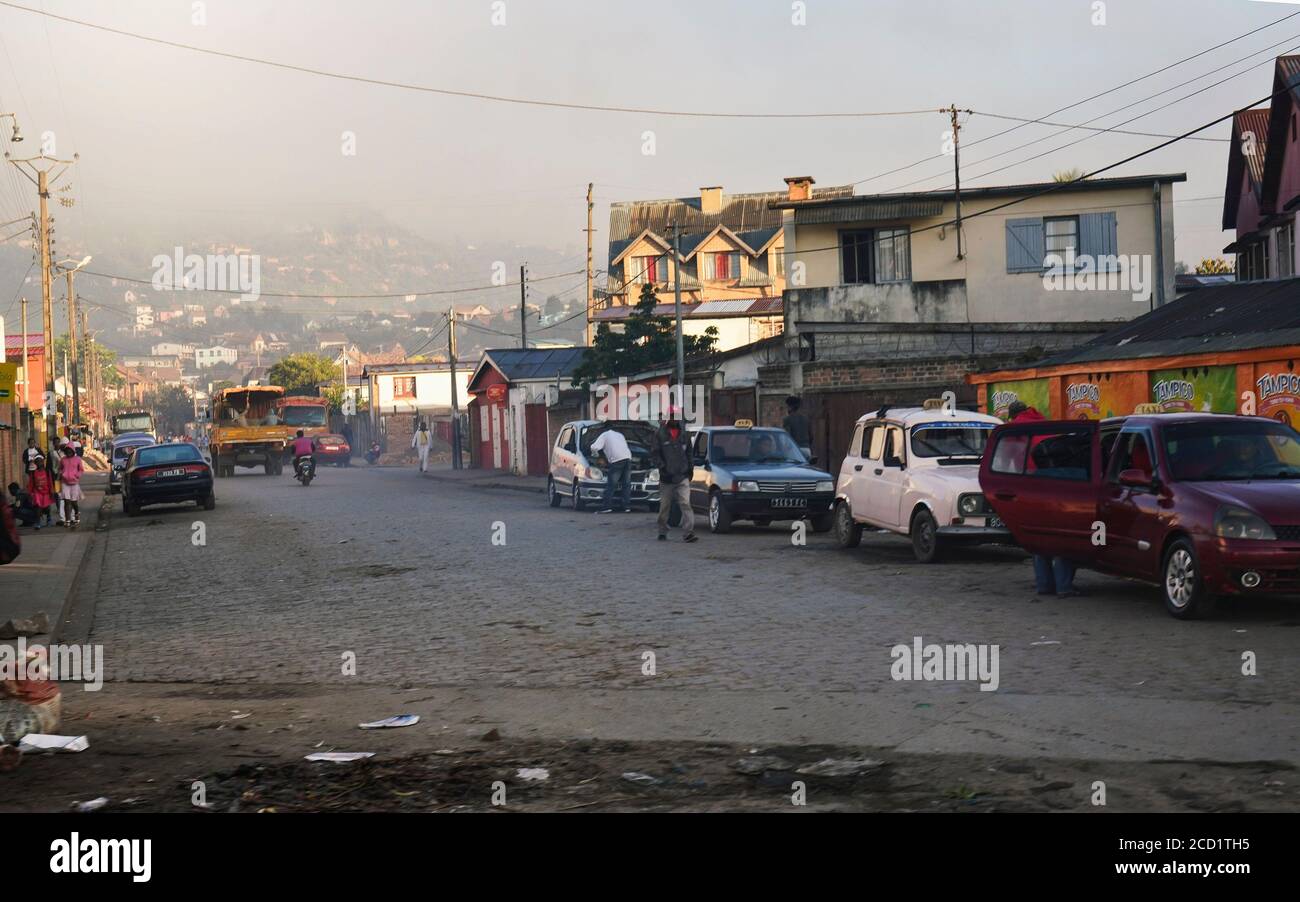 Fianarantsoa, Madagascar - 06 de mayo de 2019: Escena matutina en Fianarantsoa - personas que caminan por la calle, los niños van a la escuela, los coches, en su mayoría los taxis aparcados lado Foto de stock