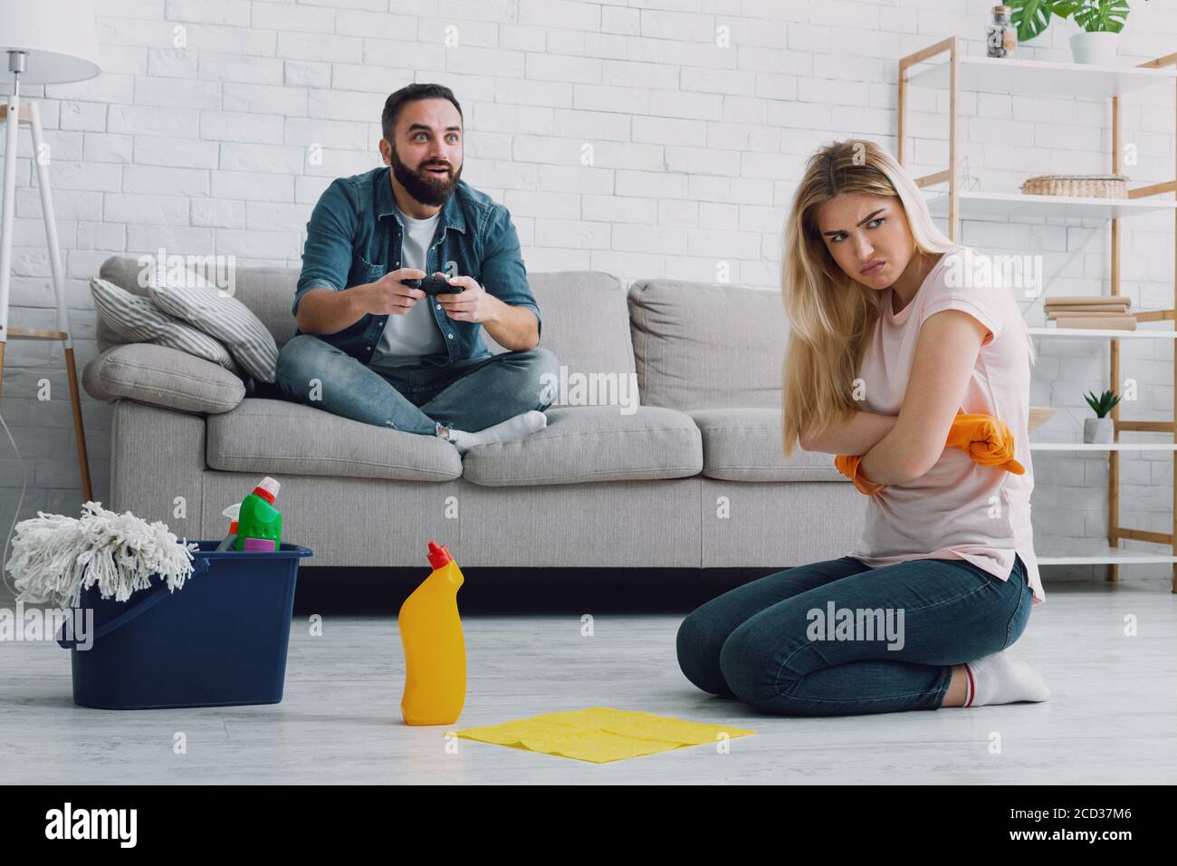 Mujer ofendida doblando sus manos con guantes en el pecho y no quiere limpiar el apartamento Foto de stock