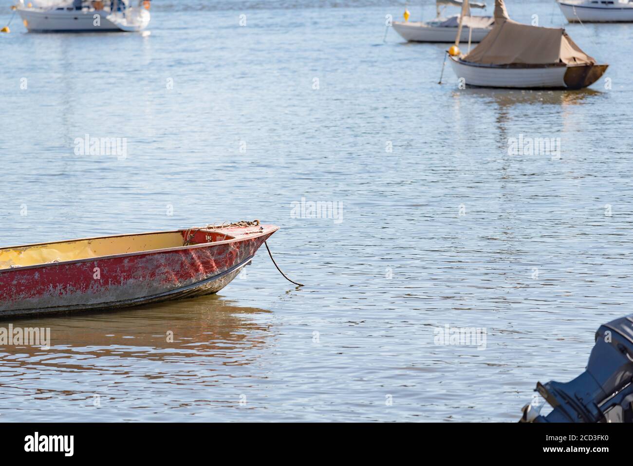 Un bote abierto o un flaco anclado cerca de barcos de vela en las tranquilas aguas del río Hawkesbury cerca de la isla de Dangar, Nueva Gales del Sur, Australia Foto de stock