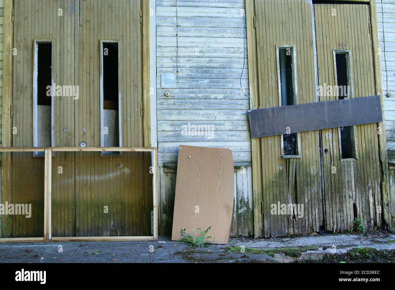 Dos puertas de madera de un edificio abanizado, una puerta es martillada cerrada con plancha de madera Foto de stock
