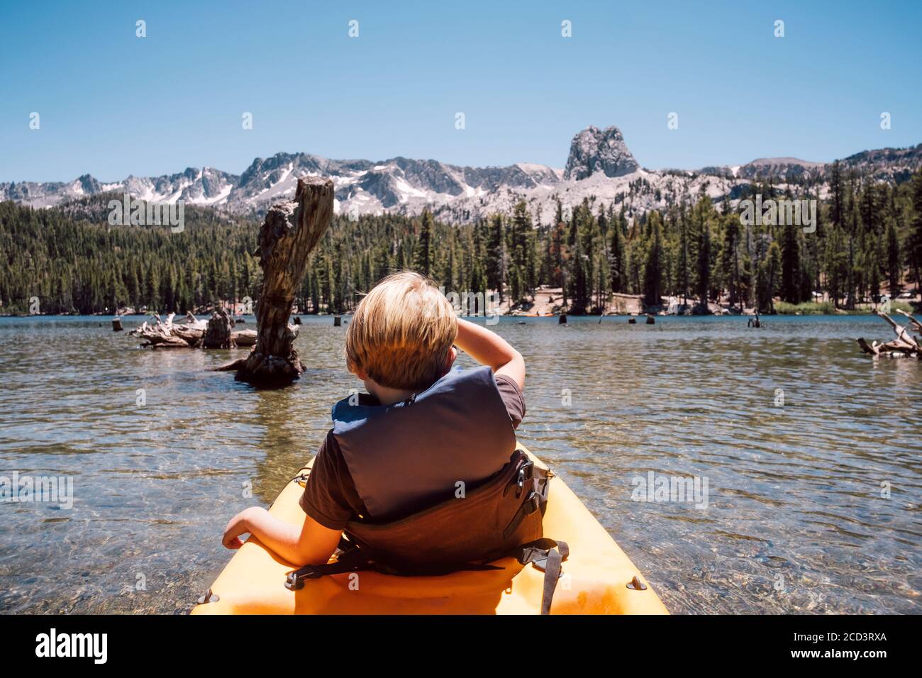 Vista trasera del niño sentado en kayak en el Lago Mary, Mammoth Lakes, California, Estados Unidos. Foto de stock
