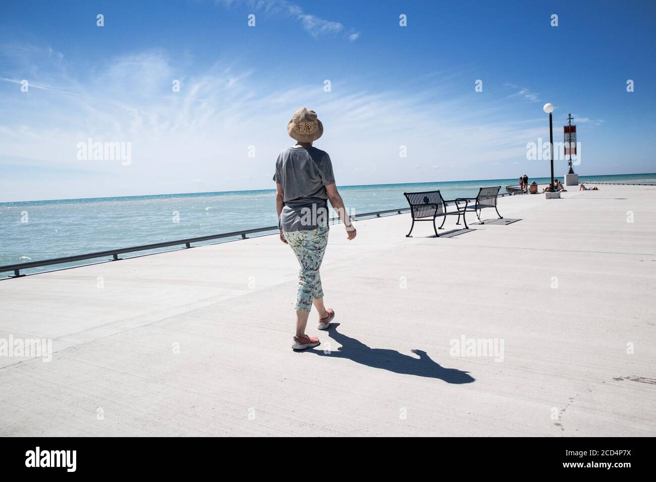 Una mujer paseando por el muro del mar en Bayfield, Ontario. Foto de stock