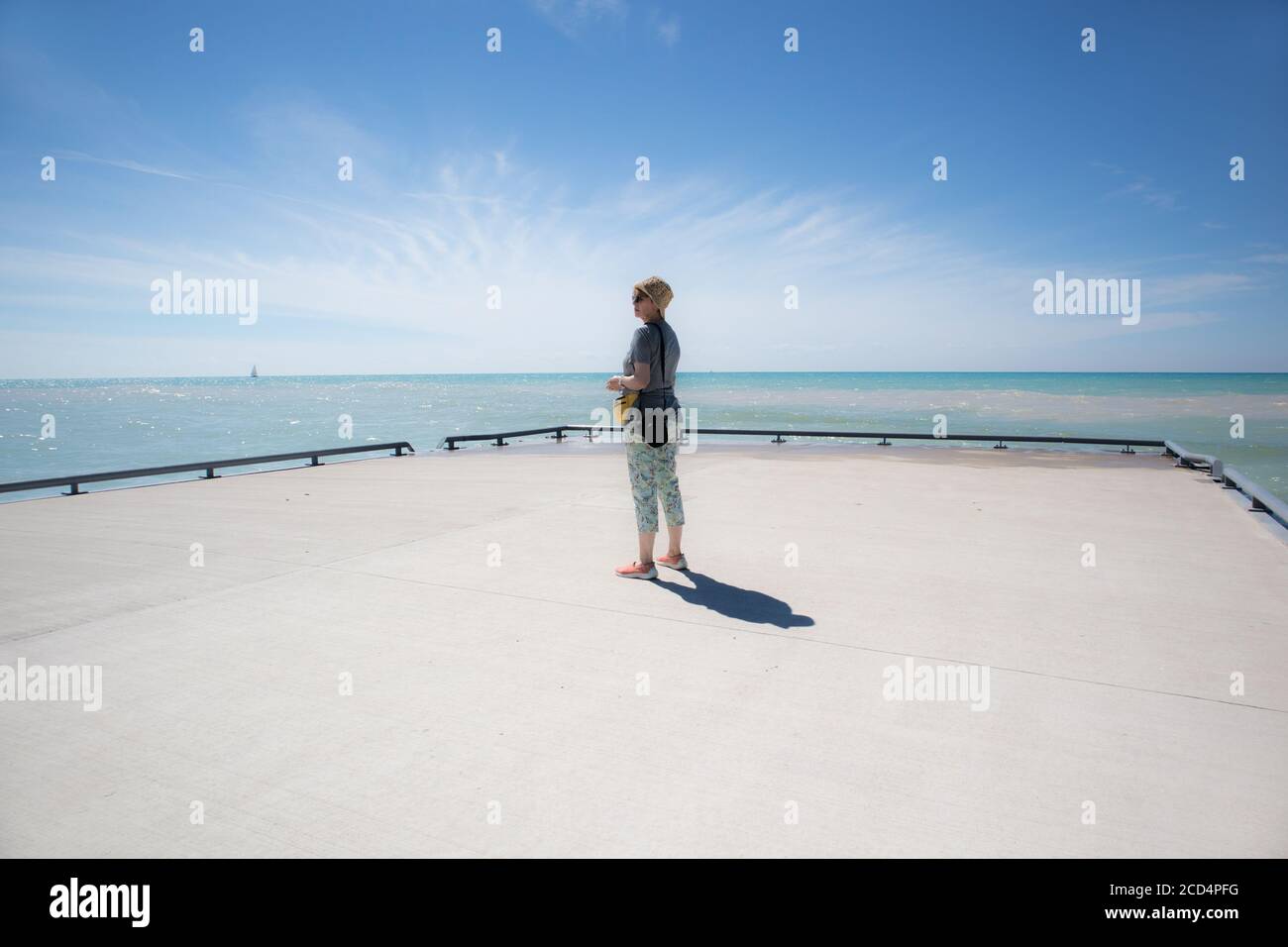 Mujer al final del muelle mirando la inmensidad. Foto de stock