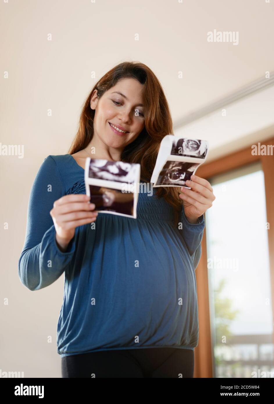 Mujer embarazada joven comparación de las exploraciones médicas del bebé Foto de stock