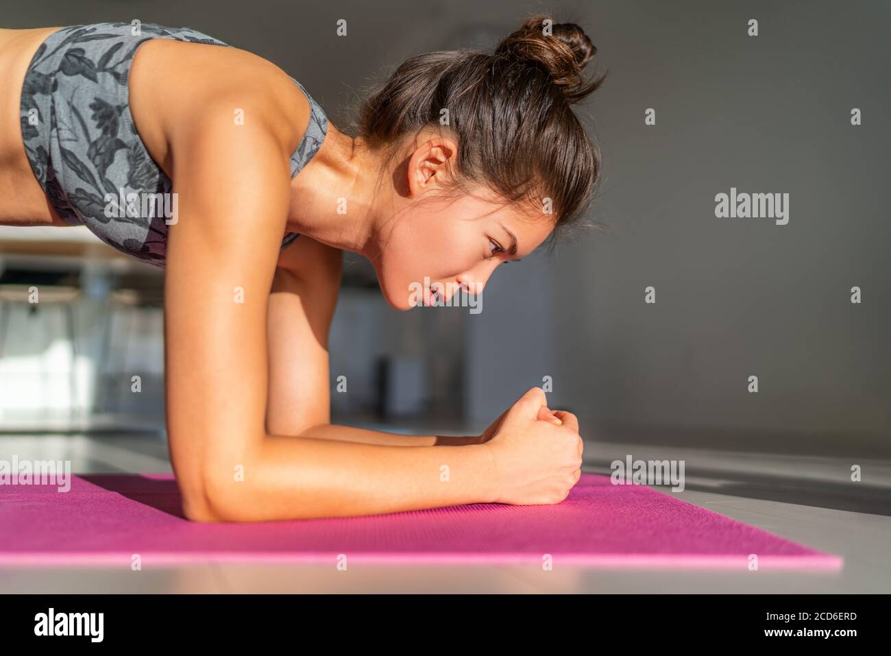 Ejercicio en casa, entrenamiento en casa chica entrenamiento en el interior del piso ejercicios en la alfombra de ejercicio en el apartamento. Mujer asiática planeando hacer yoga de peso corporal Foto de stock