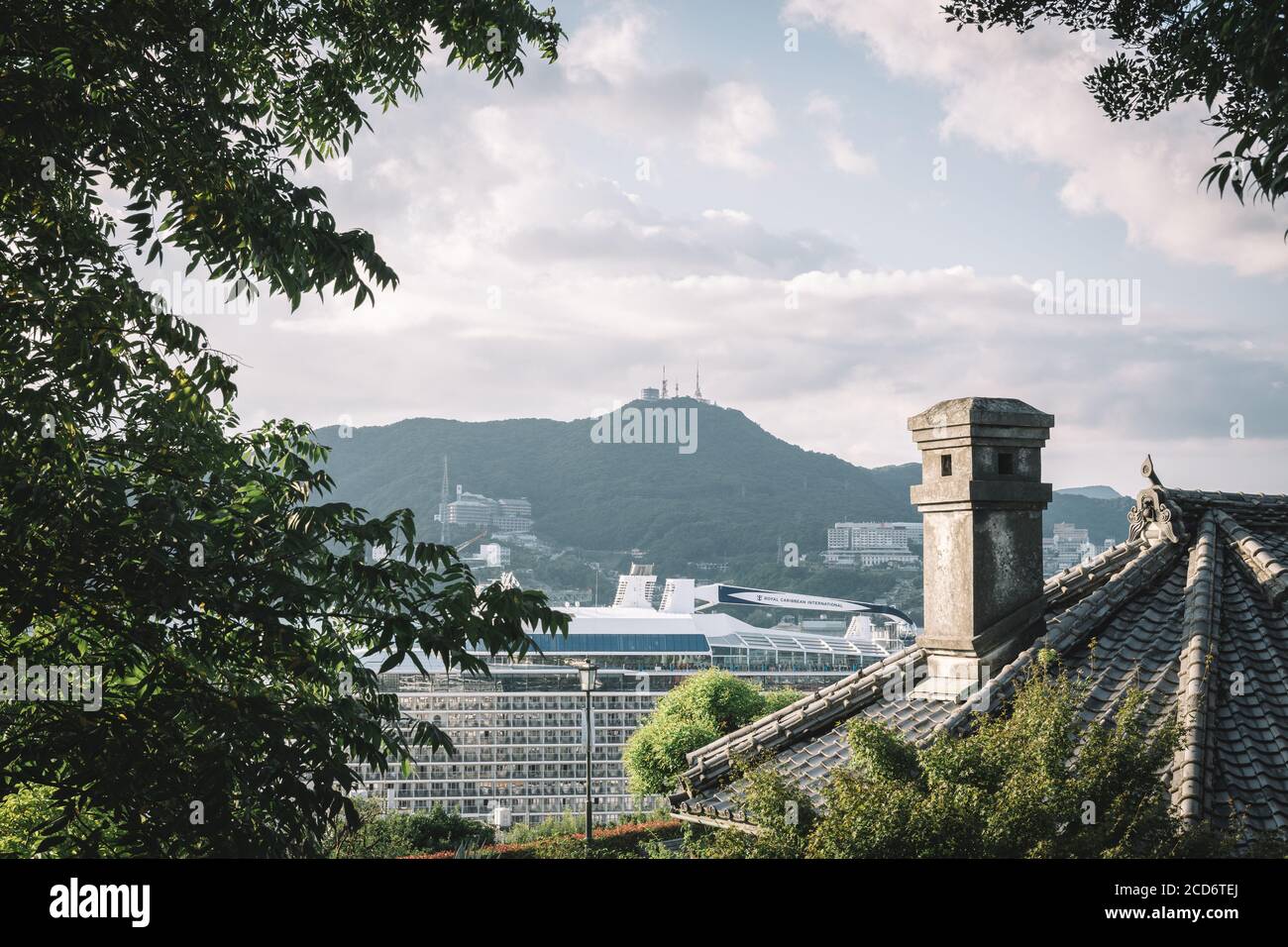 Glover Garden, Nagasaki, Kyushu, Japón - Chimenea y techo de la antigua casa japonesa y un enorme crucero en frente de la montaña Inasa. Foto de stock