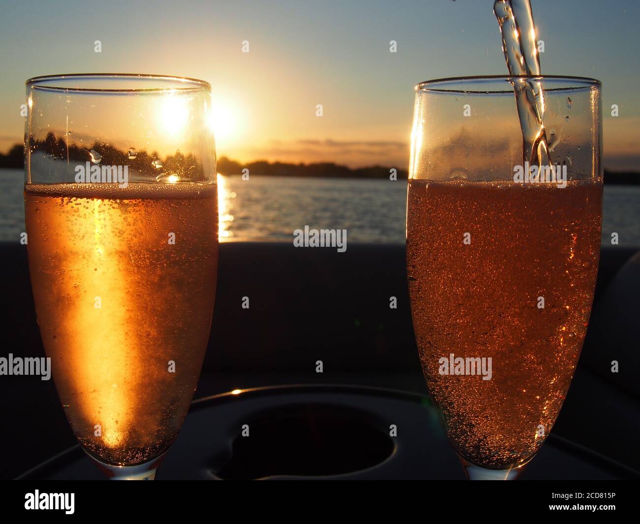 Un par de copas de champán llenas de rosas espumosas puesta de sol Foto de stock