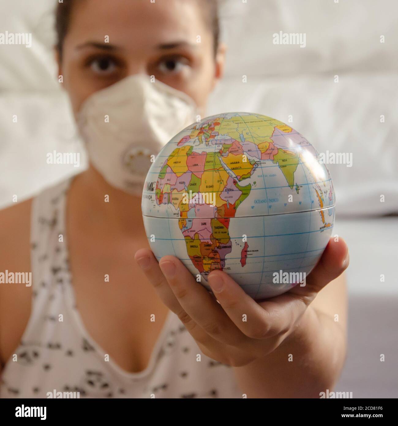 mujer blanca usando máscara de protección sostiene un globo pequeño con su mano Foto de stock