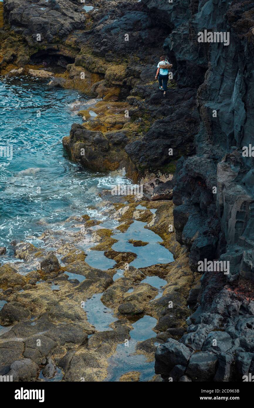 España, Islas Canarias, la Palma, pescador caminando sobre roca volcánica junto al mar Foto de stock