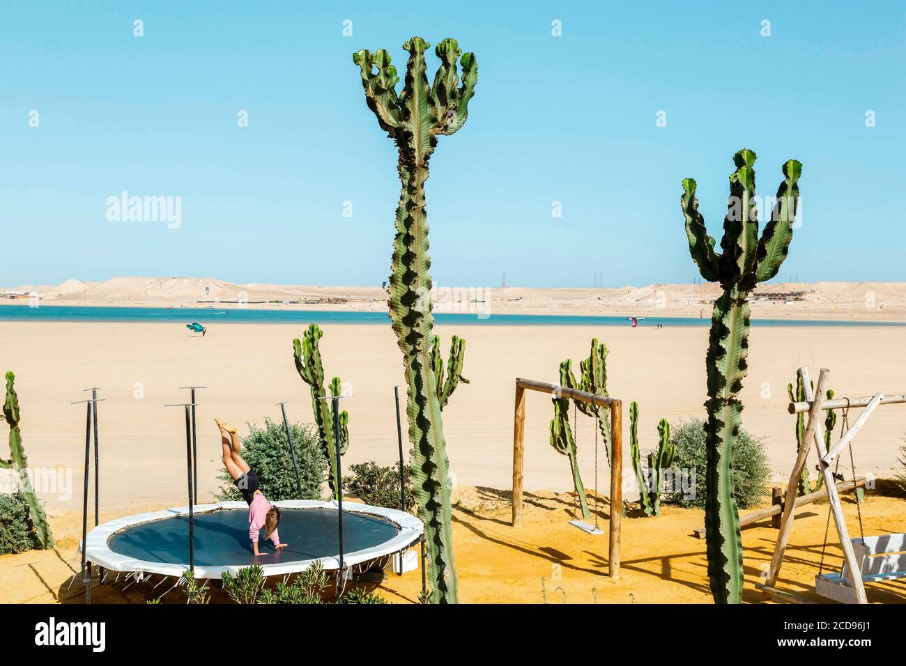 Marocco, Oued Ed-Dahab, Dakhla, Ocean Vagabond Resort, niña jugando en un trampolín junto al mar en un clima tropical y desértico Foto de stock