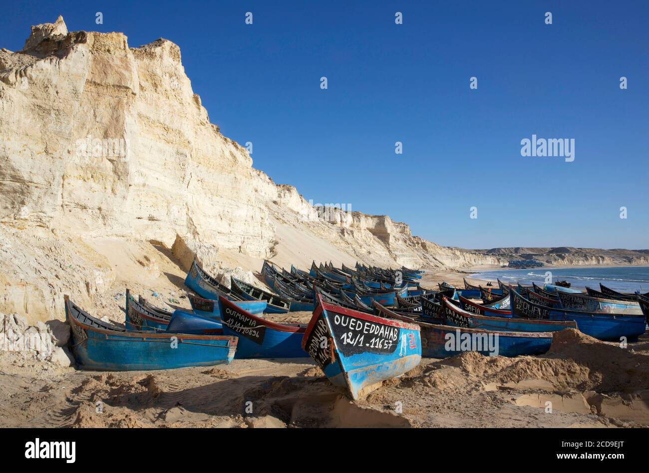 Marruecos, Sahara Occidental, Dakhla, barcos de pesca azules varados en la playa de Araiche bordeada de un acantilado Foto de stock
