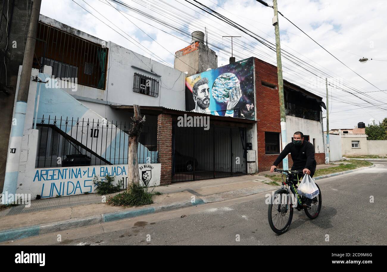 Un hombre monta su bicicleta fuera de una casa con un graffiti del argentino Lionel Messi, cerca de su casa infancia, en Rosario, Argentina 27 de agosto de 2020. REUTERS/Agustin