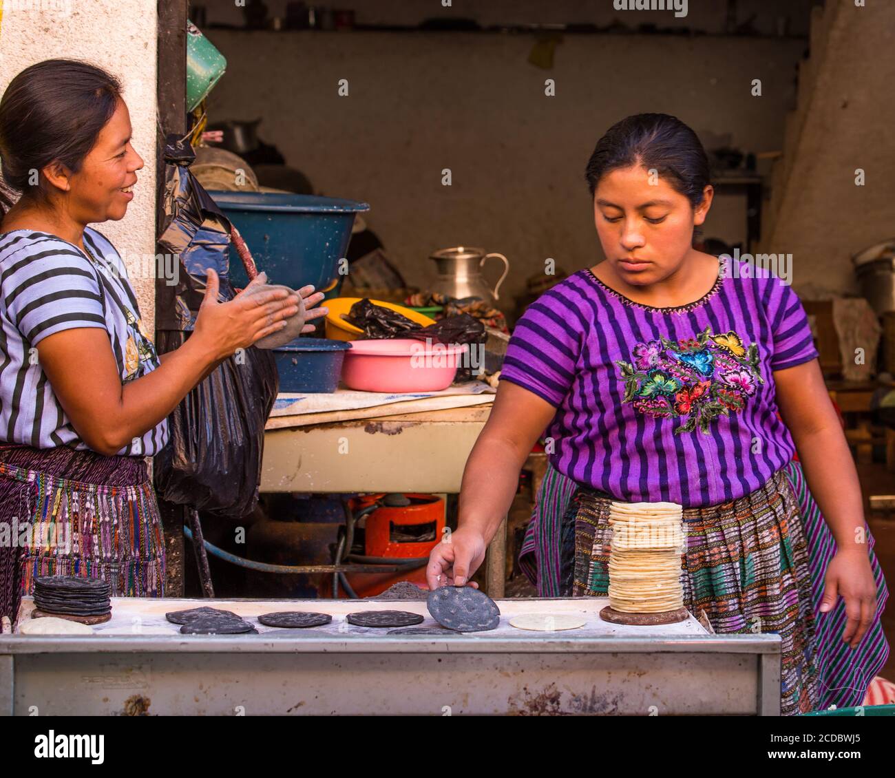Dos mujeres mayas de Tzutujil con atuendo tradicional hacen tortillas
