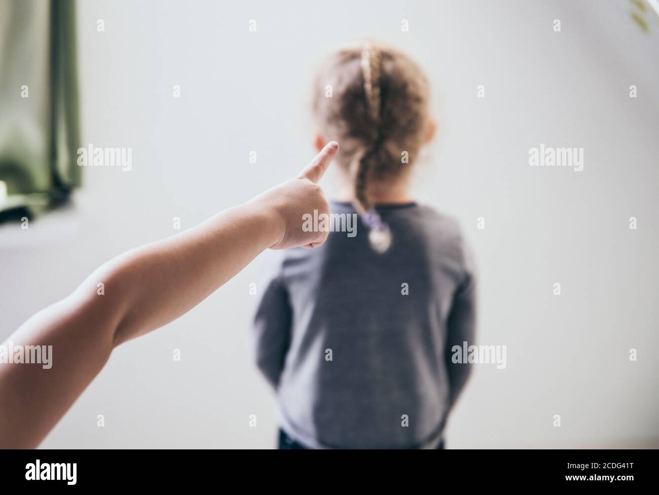 El niño intimamente apuntando con el dedo a la víctima borrosa irreconocible y hablando detrás de la espalda. Concepto de intimidación. Foto de stock