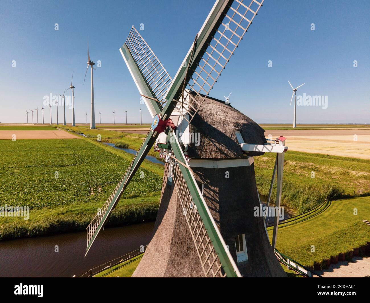 Antiguo molino de viento en combinación con nuevos aerogeneradores que generan limpio energía Foto de stock