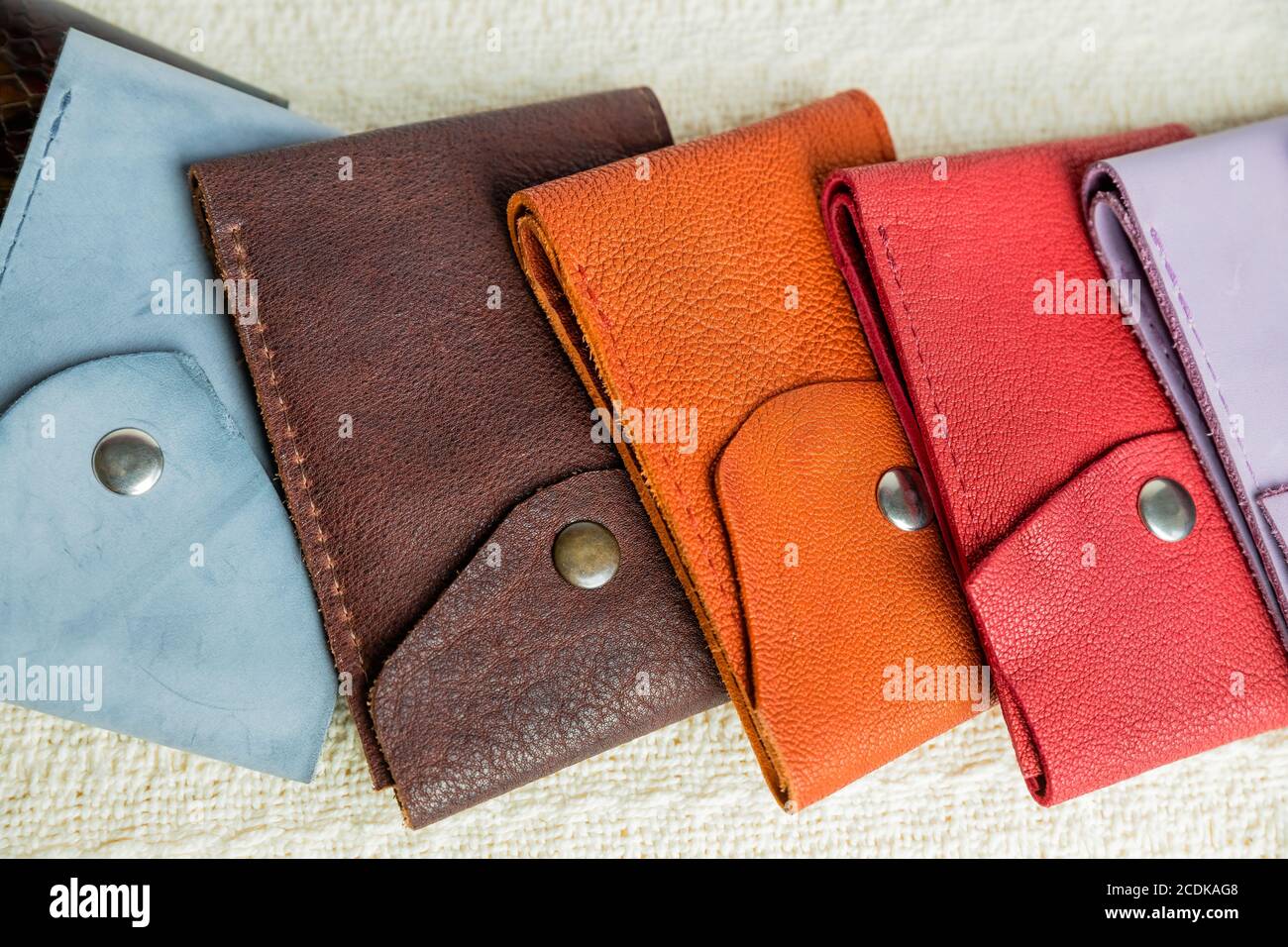 Carteras de cuero de colores.carteras de hechas a mano de diferentes formas sobre un fondo textil beige. Venta de artículos de cuero punto Fotografía de stock - Alamy