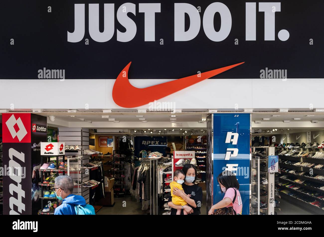 Los peatones que llevan máscaras pasan por delante de la Marca  estadounidense multinacional de ropa deportiva Nike store, logo, con un  eslogan 'Just do It' en Hong Kong Fotografía de stock -