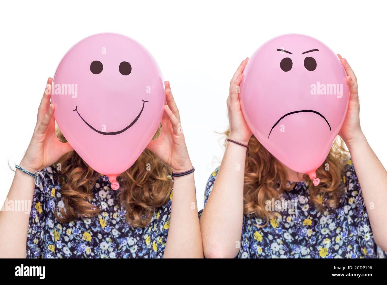Dos chicas sosteniendo globos rosas con expresiones faciales para la cabeza Foto de stock