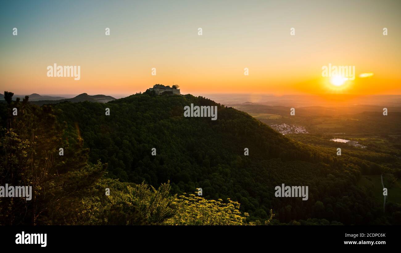 Alemania, Vista aérea escénica sobre los verdes valles de la naturaleza de las albas de suabia paisaje y ruinas del castillo de hohenneuffen en la montaña en la puesta de sol de color naranja cálido lig Foto de stock