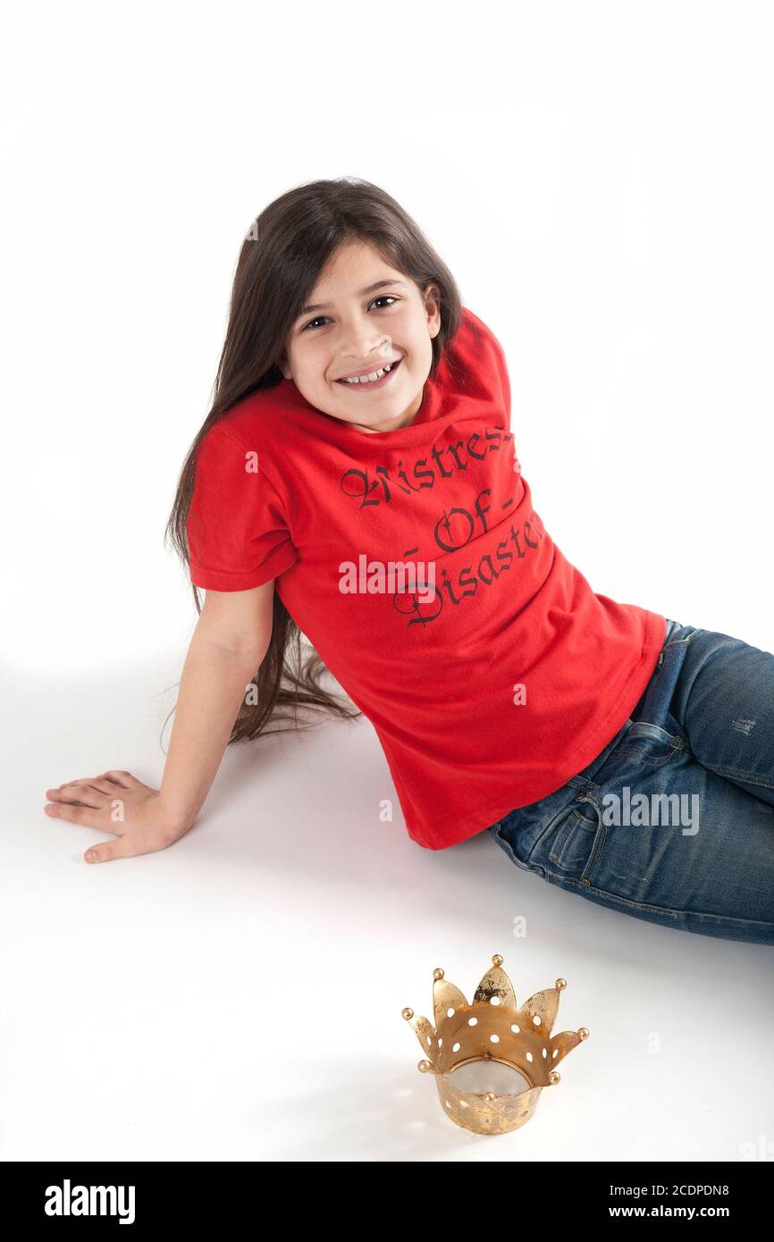 Chica joven de aspecto feliz en una camiseta roja con cheeky eslogan y corona de princesa Foto de stock