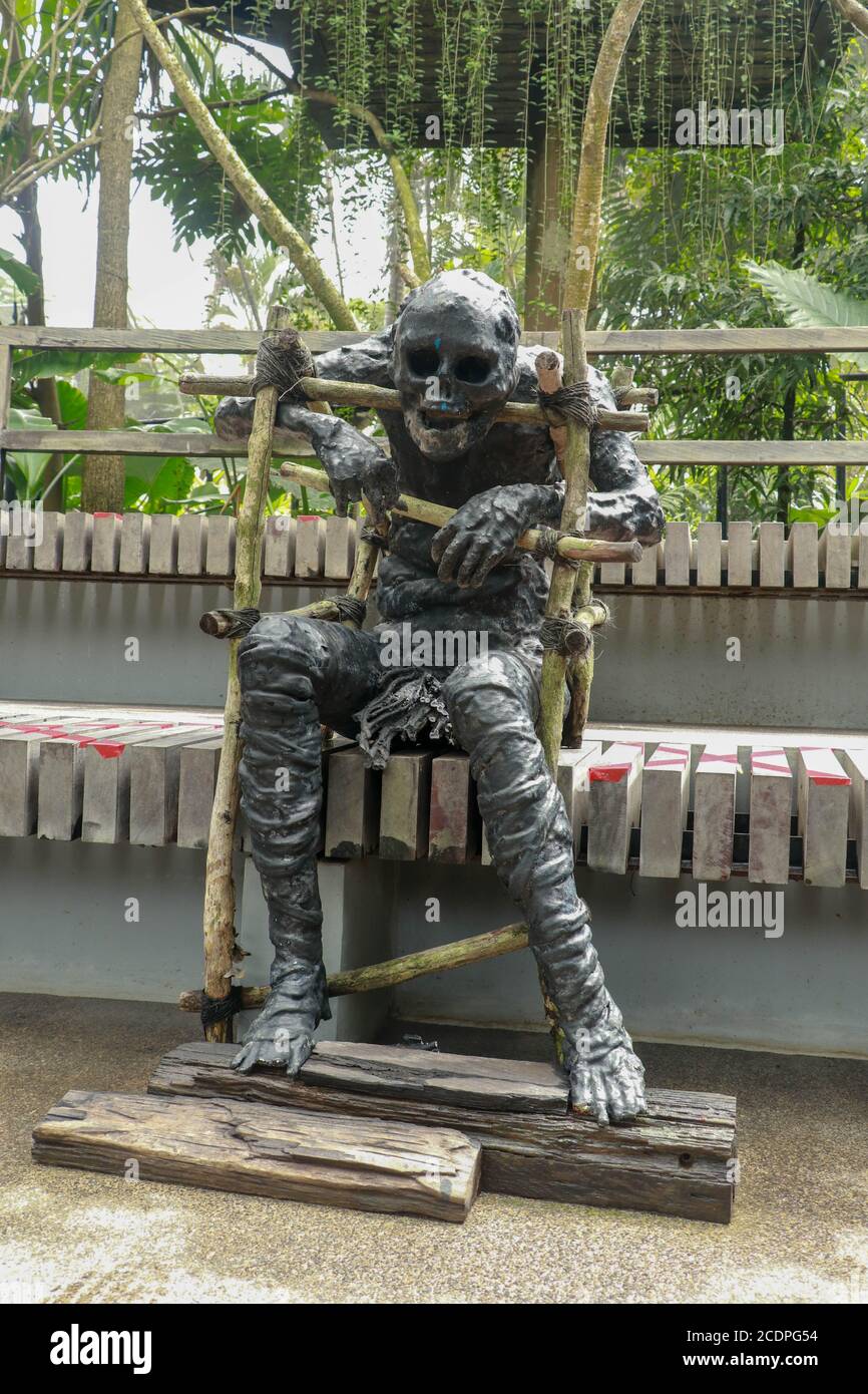 Mamá cubierta de ropa en calavera decorada en halloween cosplay y luz sobre fondo oscuro. Una figura de una momia negra sentada en un banco. Zombie en Foto de stock