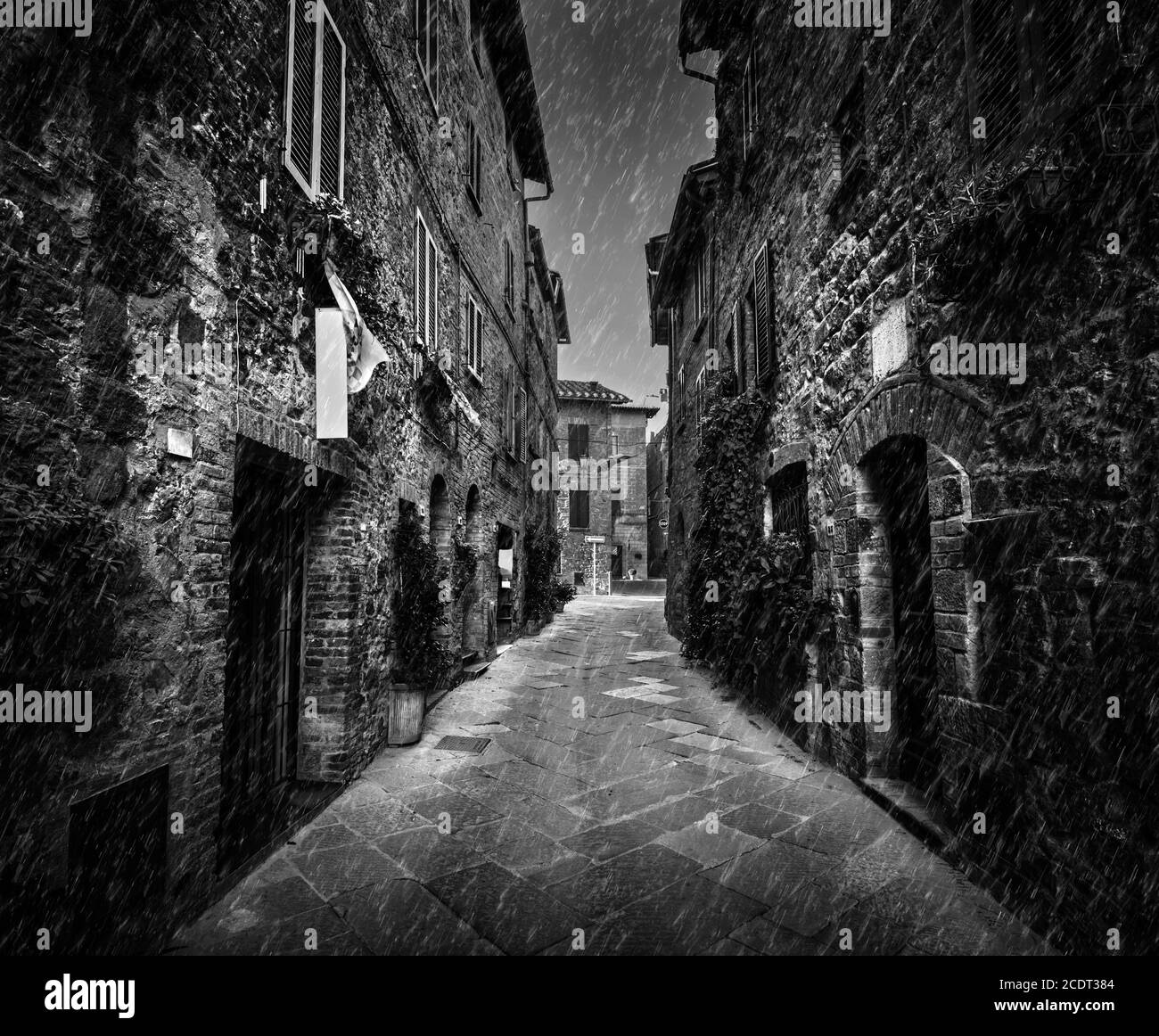 Calle oscura en una vieja ciudad italiana en Toscana, Italia. Lluvia, blanco y negro Foto de stock