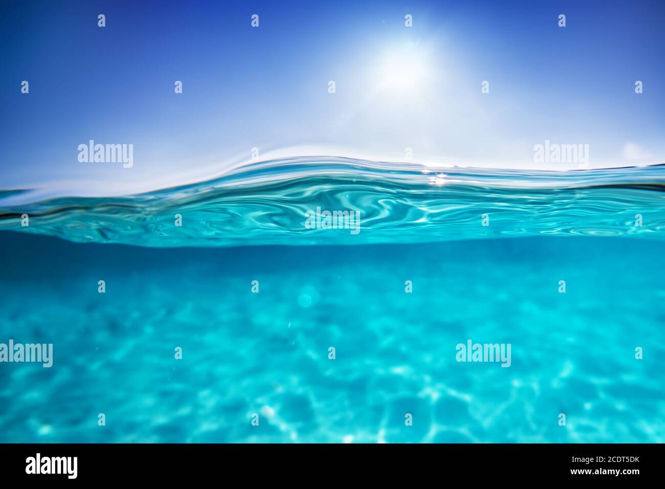 Medio tiro submarino, agua clara y cielo azul soleado. Océano tropical Foto de stock